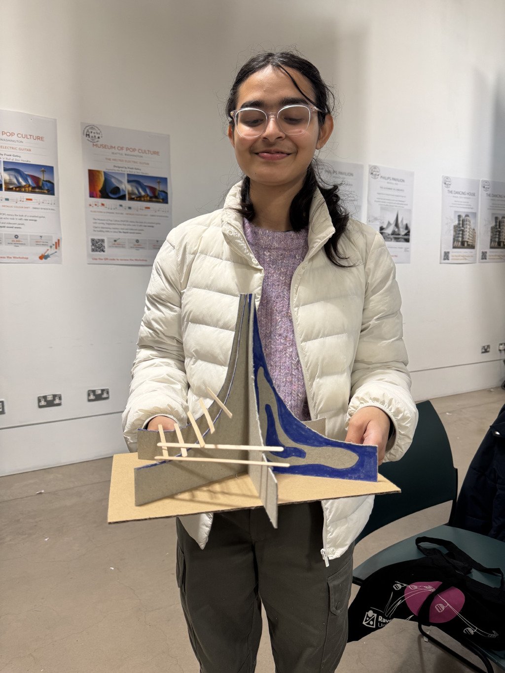 A teenage girl proudly holding her card and wooden-stick model