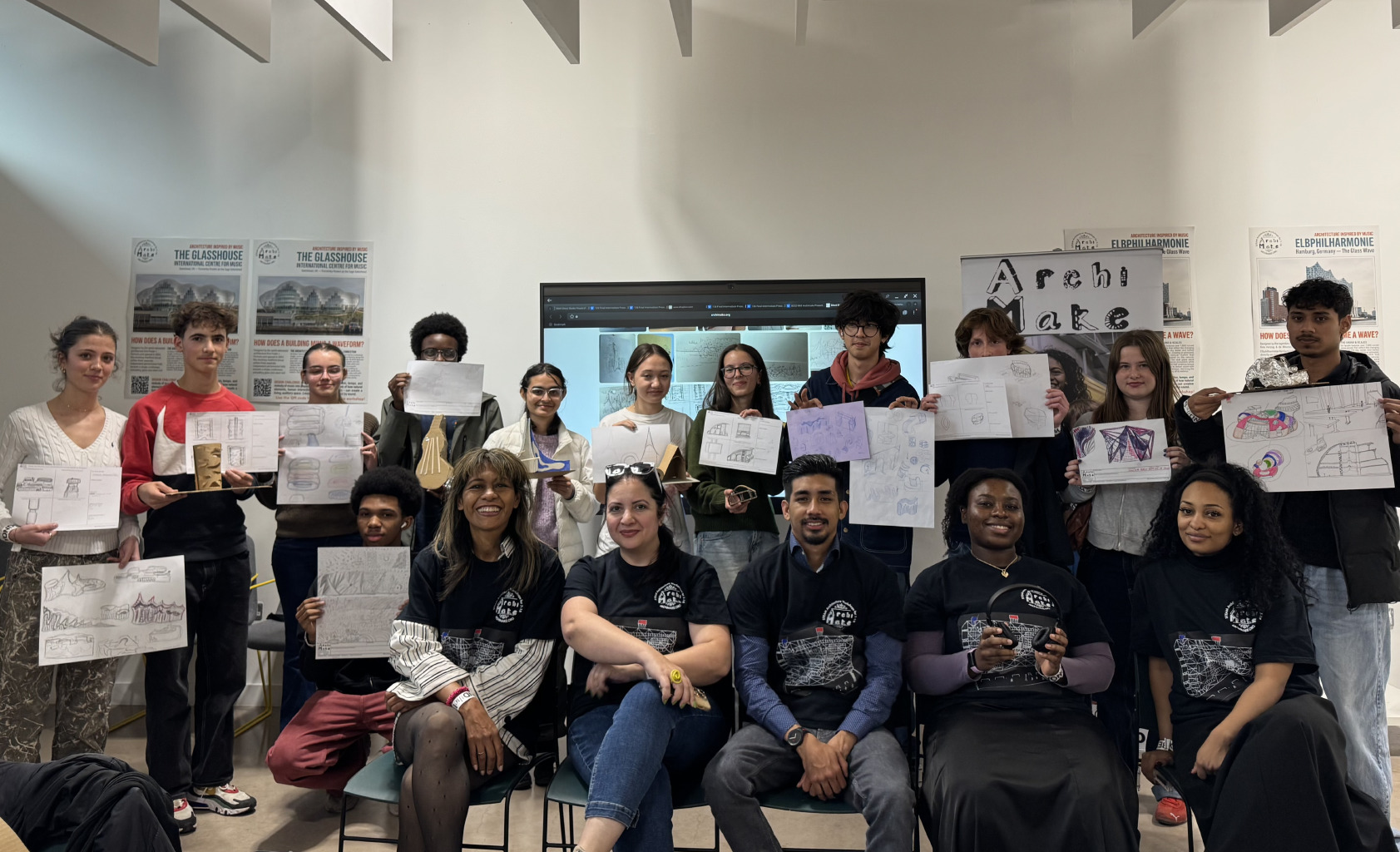 A group of teenage Archimakers holding up their design drawings with their tutors