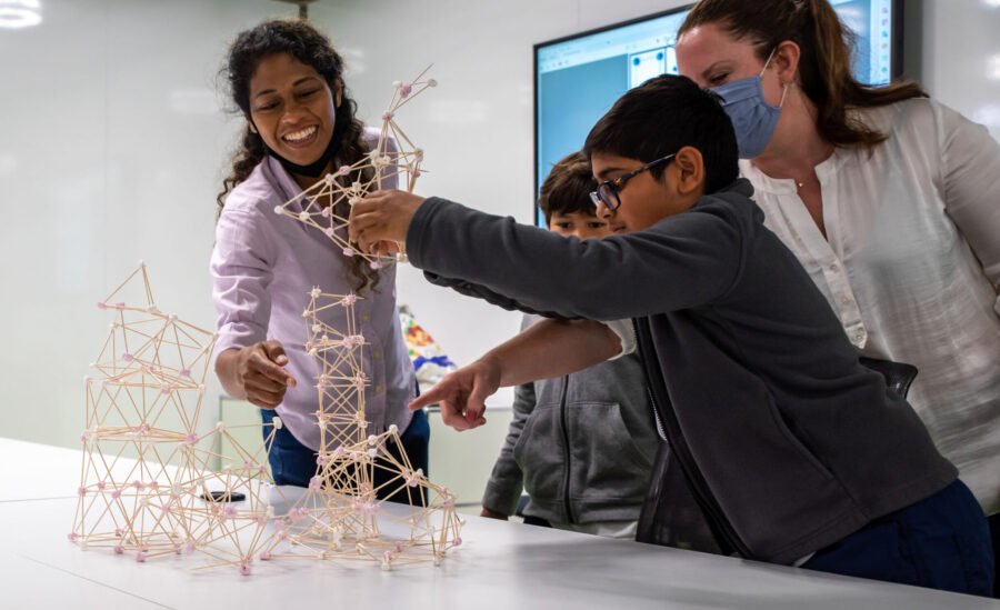 Children and tutors building a tall stick-and-joint model structure